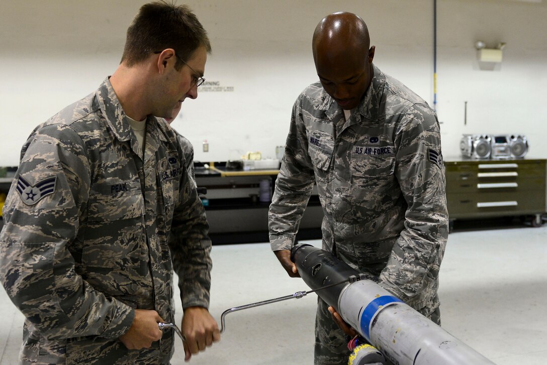 U.S. Air Force Senior Airmen Garrett Peak and Jarrett Ware, 1st Maintenance Squadron ammunition technicians, take apart a Captive Air Training Missile 9M at Langley Air Force Base, Va., Oct. 19, 2015. During periodic training missions, technicians inspect Guidance Control Sections of missiles. (U.S. Air Force photo by Airman 1st Class Derek Seifert/ Released)