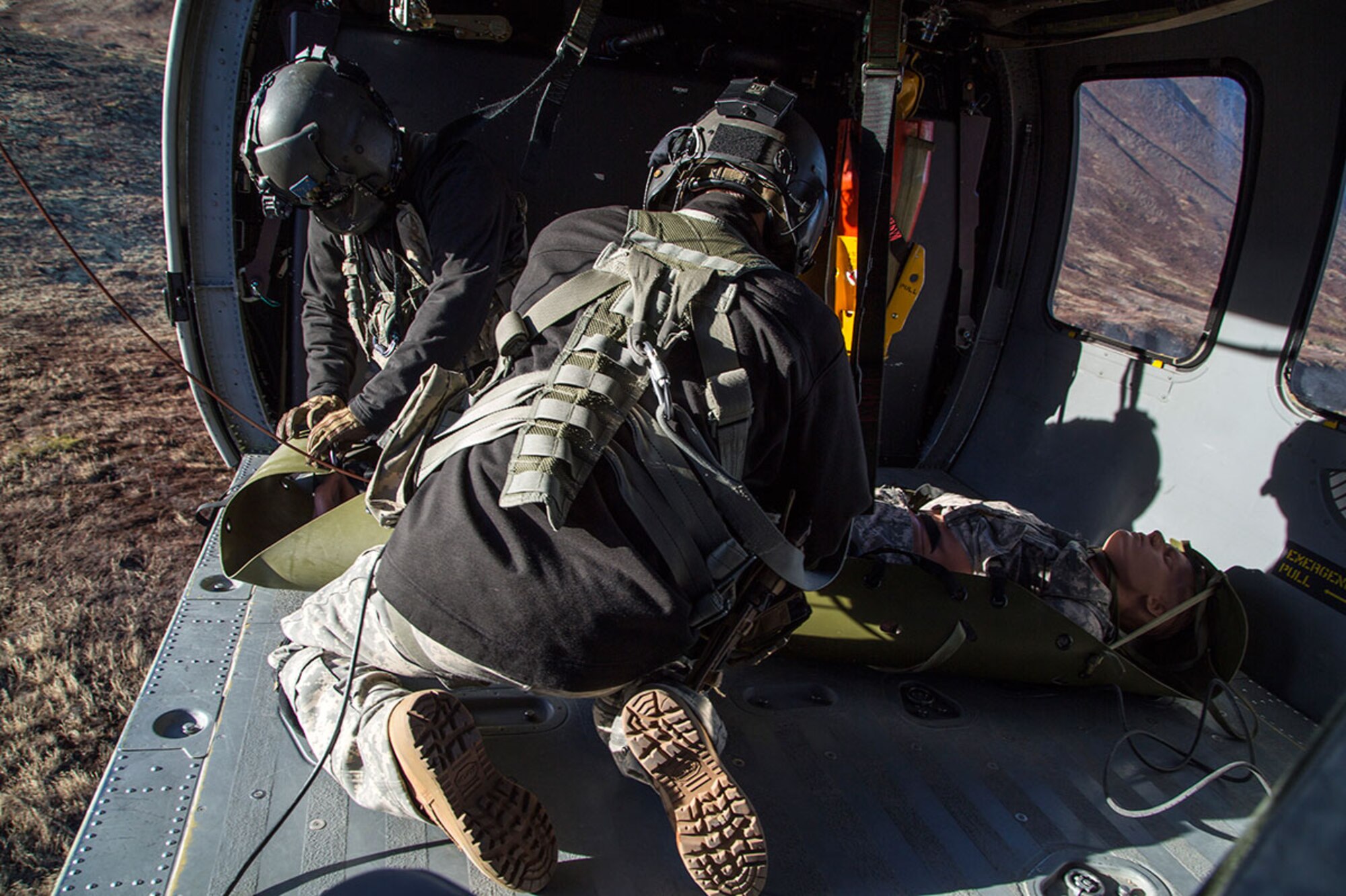 Alaska Army National Guard Staff Sgt. Kevan Katkus, background, and Sgt. Bradley McKenzie, UH-60 Black Hawk helicopter crew chiefs assigned to 1st Battalion, 207th Aviation Regiment, recover a simulated casualty while conducting rescue hoist training on Joint Base Elmendorf-Richardson, Oct. 21, 2015. The casualty evacuation exercise was coordinated with Soldiers assigned to 1st Battalion (Airborne), 501st Infantry Regiment, to prepare for future emergencies and maintain operational readiness. (U.S. Air Force photo/Alejandro Pena)