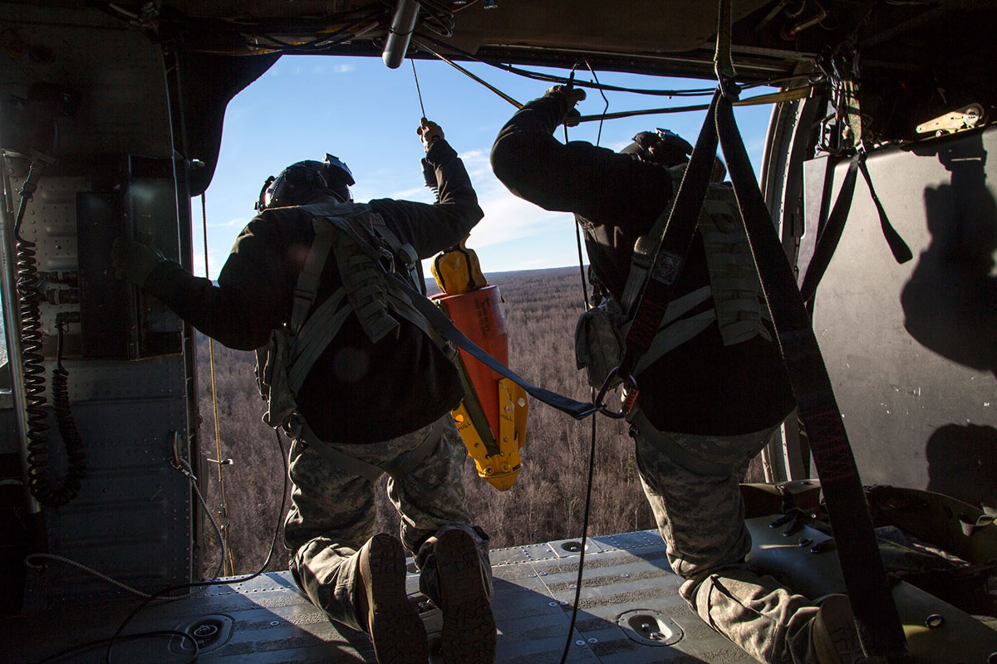 Alaska Army National Guard Sgt. Bradley McKenzie, left, and Staff Sgt. Kevan Katkus, UH-60 Black Hawk helicopter crew chiefs assigned to 1st Battalion, 207th Aviation Regiment, deploy a jungle penetrator while conducting rescue hoist training on Joint Base Elmendorf-Richardson, Alaska, Oct. 21, 2015. The training included operating a jungle penetrator device and practicing a simulated casualty evacuation with Soldiers assigned to 1st Battalion (Airborne), 501st Infantry Regiment. (U.S. Air Force photo/Alejandro Pena)