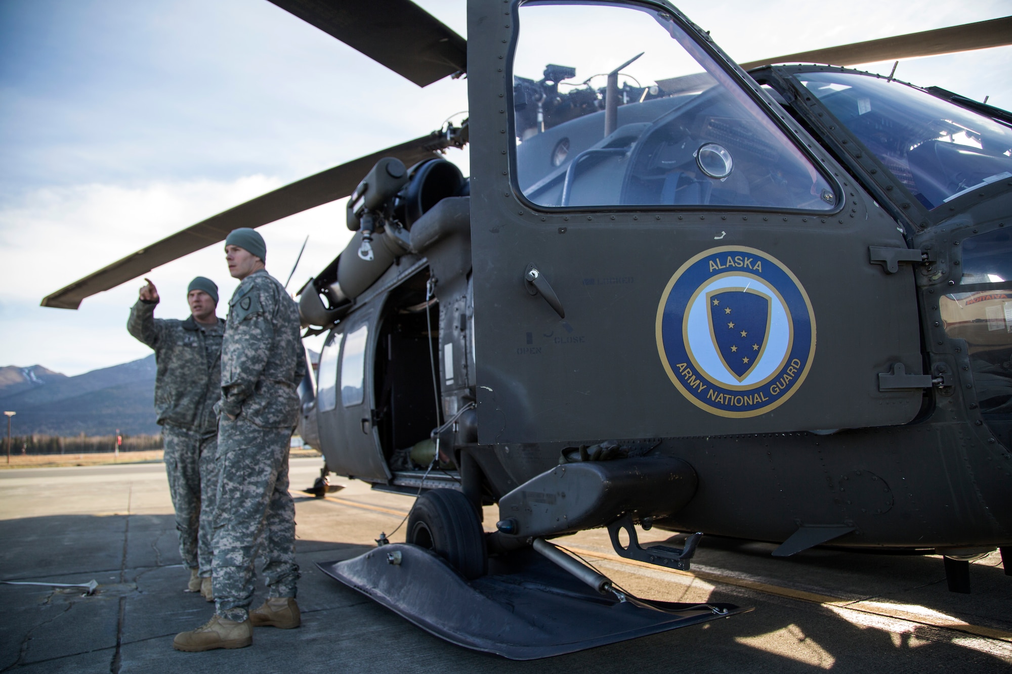 Alaska Army National Guard Chief Warrant Officer 4 Mark Ward, left, and Capt. Zachary Miller, UH-60 Black Hawk helicopter pilots assigned to 1st Battalion, 207th Aviation Regiment, confer with each other before conducting rescue hoist training on Joint Base Elmendorf-Richardson, Alaska, Oct. 21, 2015. The training included deploying a jungle penetrator device and practicing a simulated casualty evacuation with Soldiers assigned to 1st Battalion (Airborne), 501st Infantry Regiment. (U.S. Air Force photo/Alejandro Pena)