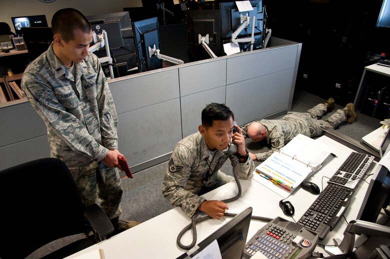 CHEYENNE MOUNTAIN AIR FORCE STATION, Colo. – Staff Sgt. Ahmad Buhari, simulated hostage, answers the phone for 1st Lt. Miles Tran, simulated active shooter, during an exercise in Cheyenne Mountain Air Force Station’s underground complex, Oct. 22, 2015. 721st Security Forces Squadron held a joint training exercise intended to bring together El Paso County Sheriff’s Department with Cheyenne Mountain AFS personnel in a training environment in preparation for potential real-world situations. (U.S. Air Force photo by Senior Airman Tiffany DeNault)