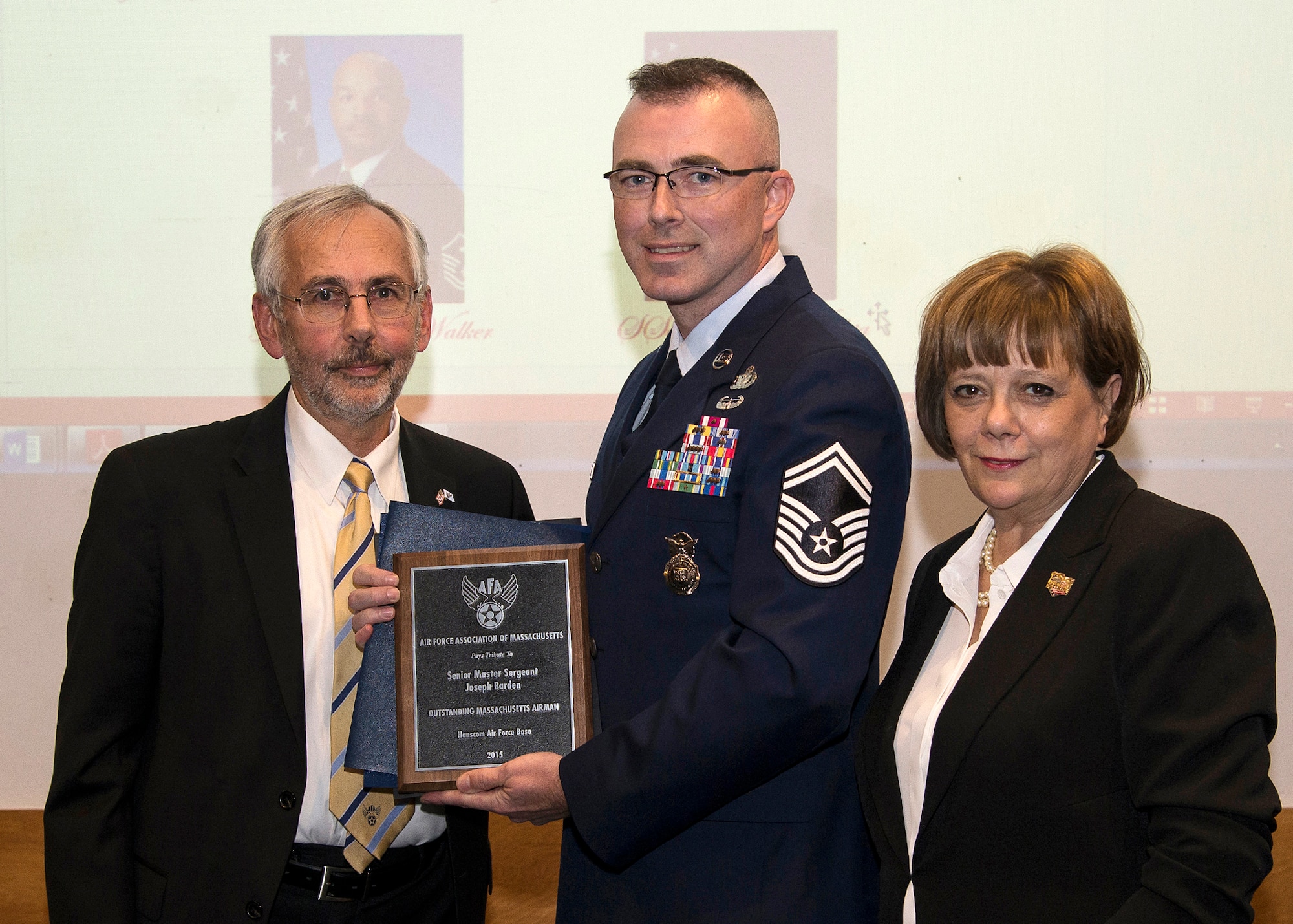 Joseph Bisognano, Air Force Association of Massachusetts president, presents Senior Master Sgt. Joseph Barden, 66th Security Forces Squadron operations superintendent, with a plaque in recognition of his selection as one on the commonwealth's Top 5 Massachusetts Airmen during an awards dinner at the U.S.S. Constitution in Charlestown, Mass., Oct. 24, while Yvonne Thurston, Minuteman Chapter of the AFA, stands by. Master Sgt. Kevin Walker, formerly the 319th Recruiting Squadron’s first sergeant who is now assigned to the 502d Contracting Squadron, Joint Base San Antonio, Texas, was also selected as one of the five Airmen highlighted during the event. (U.S. Air Force photo by Walter Santos)