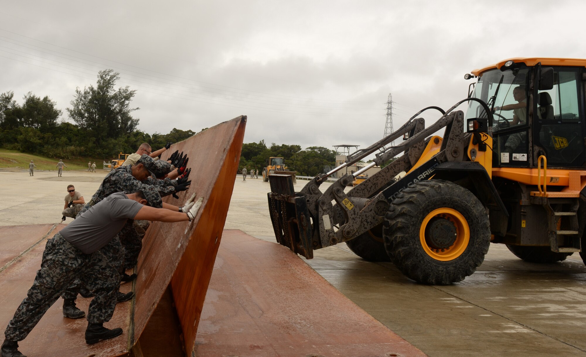 Civil engineers from the Japan Air Self Defense Force Southwestern Composite Air Division and the U.S. Air Force 18th Wing fold a fiberglass mat during the bilateral training day, Oct. 22, 2015, on Kadena Air Base, Japan. Civil engineers from Naha Air Base and Kadena Air Base improved bilateral relations by training together to repair a 50 foot crater. (U.S. Air Force photo by Senior Airman Omari Bernard)