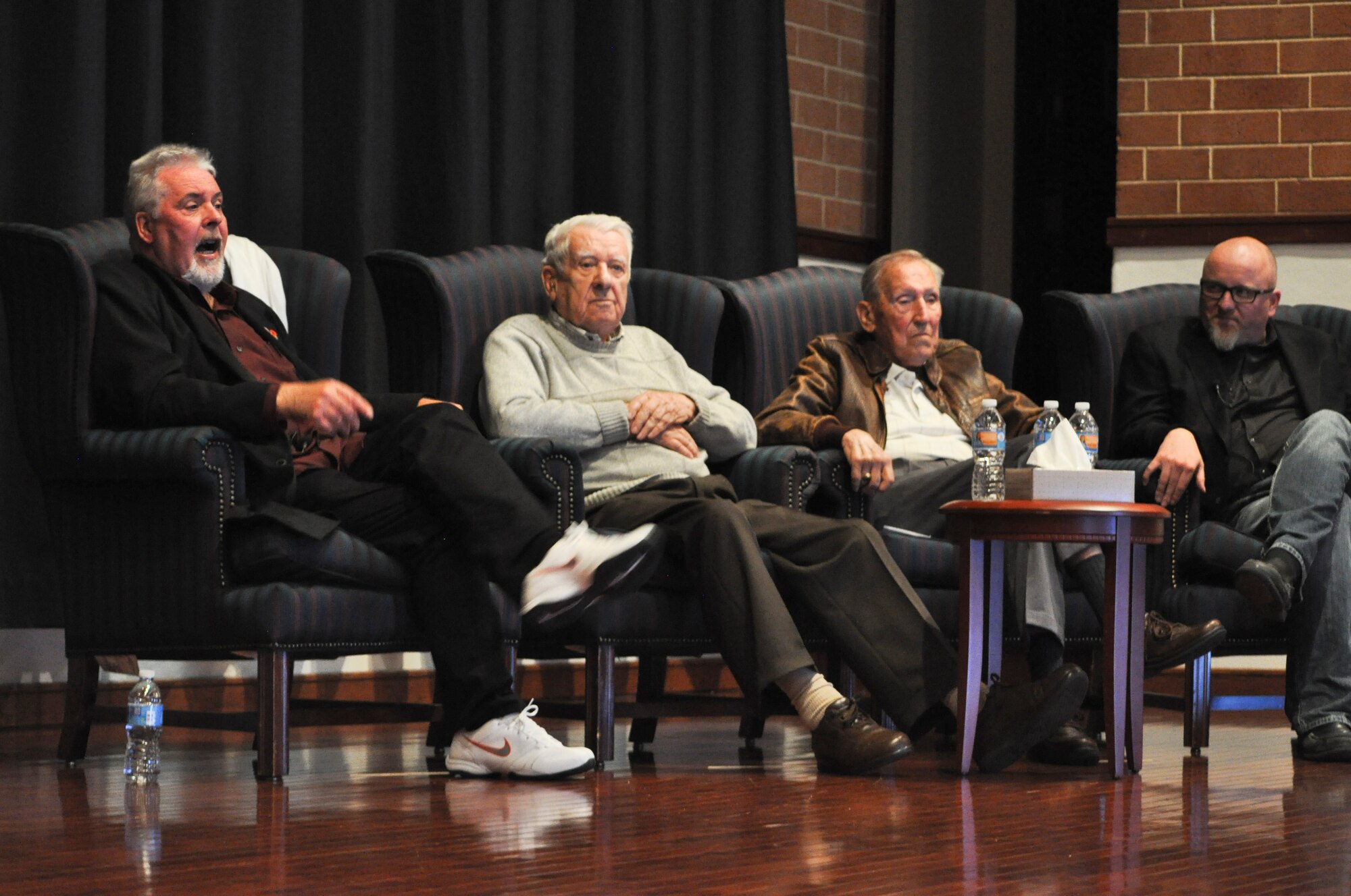 Martin King speaks while on stage with John Schaffner, Lt Col. (Ret) Bob Hansen, and Michael Lewis listen during the Battle of the Bulge symposium held at the U.S. Air Force Expeditionary Center Oct. 21, 2015. Hansen and Schaffner spoke about their experiences during WWII. After, Lewis and King presented their Emmy Award winning documentary Searching for Augusta: The Forgotten Angel of Bastogne. (U.S. Air Force Photo/Capt. Matthew Chism)