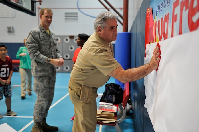(Right) U.S. Navy Capt. Timothy Sparks, 628th Air Base Wing vice commander, and Lt. Col. Ralph Thomas, 628th Mission Support Group deputy commander, begin the drug free living ceremony by leaving their hand prints and signatures during the Red Ribbon Week kickoff event at Joint Base Charleston - Air Base, S.C., Oct. 23, 2015. More than 20 children took the pledge to be drug free during this year's event. (U.S. Air Force photo/Tech. Sgt. Renae Pittman)