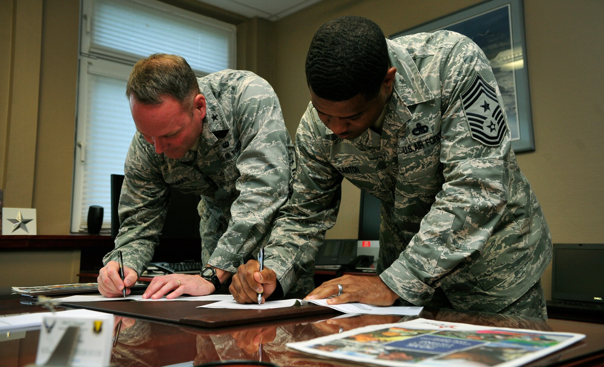 Brig. Gen. Jon T. Thomas, 86th Airlift Wing commander, and Chief Master Sgt. Phillip Easton, 86th AW command chief, sign pledge forms in support of the Combined Federal Campaign-Overseas Oct. 22, 2015, at Ramstein Air Base, Germany.  The CFC-O allows U.S. military members and U.S.  government civilian employees to donate to the charity of their choice, with more than 2,600 charities available to choose from. (U.S. Air Force photo/Airman 1st Class Larissa Greatwood)