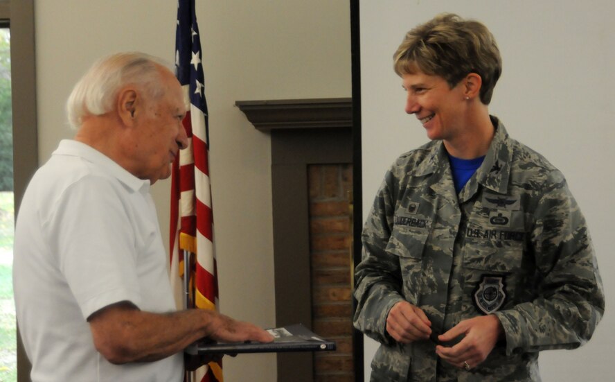 Wolfgang Samuel presents Col. Leah Lauderback, National Air and Space Intelligence Center commander, with a copy of “Watson’s Whizzers” during the NASIC Alumni Association annual meeting Friday, Oct. 23, 2015 at Wright-Patterson Air Force Base, Ohio. Samuel, a retired Air Force lieutenant colonel, is a former NASIC executive officer and an author. (U.S. Air Force photo by Master Sgt. Tammie Moore)