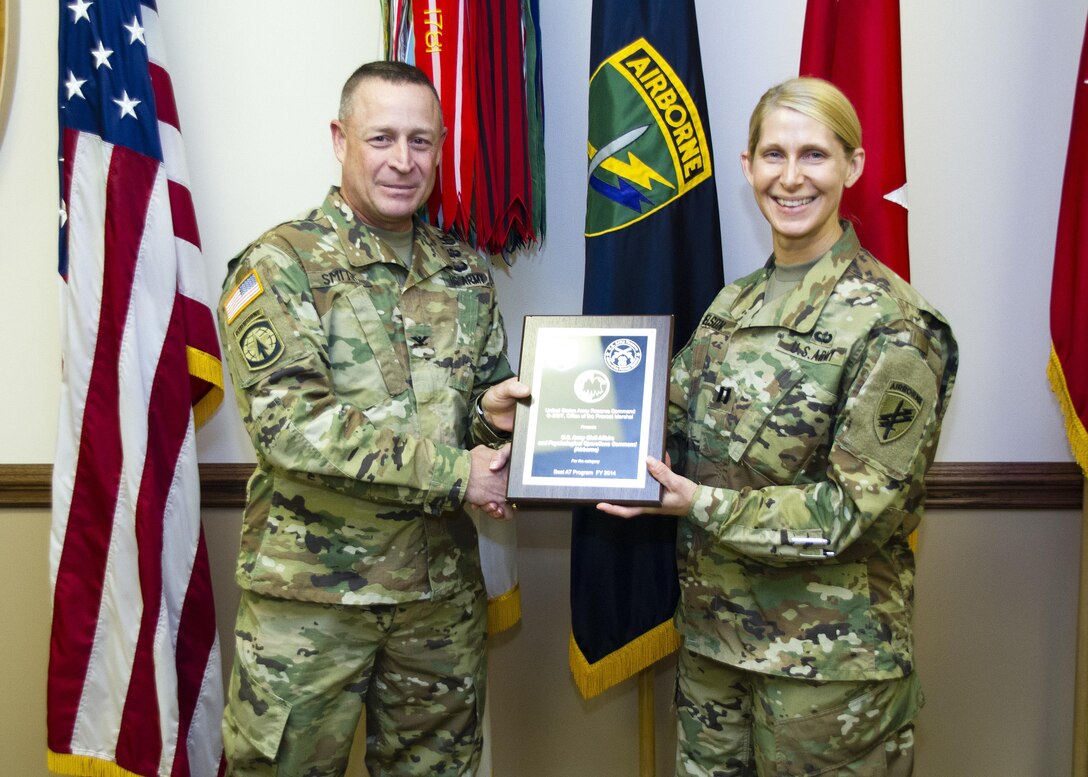 Col. Douglas Smith, the U.S. Army Reserve Command’s G-3-4, presents Capt. Wendy Nelson with the 2014 USARC’s Best Antiterrorism Program during a ceremony held Oct. 26 at Fort Bragg, N.C. The U.S. Army Civil Affairs and Psychological Operations Command (Airborne) won the award for the second year in a row. Nelson is the command’s antiterrorism program manager. (Army Reserve photo by Master Sgt. Mark Bell/released)