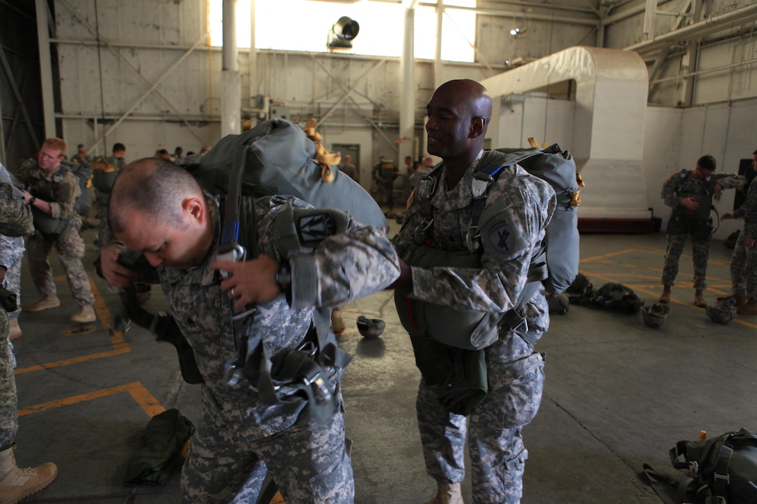 U.S. Army Staff Sgt. Edward Reagan, a squad leader with 982nd Combat Camera Signal Co. gets assistance rigging his parachute from Lt. Col. David H. Haigler, the G6 for U.S. Army Civil Affairs and Psychological Operations Command (USACAPOC), during airborne operations at Fort Bragg, N.C., Oct. 26, 2015. Staff Sgt. Reagan is a guest jumper with USACAPOC, as they conduct airborne operations in order to maintain proficiency and receive familiarization with the C-27 aircraft. Photo by Sgt. 1st Class Sean A. Foley (Released)