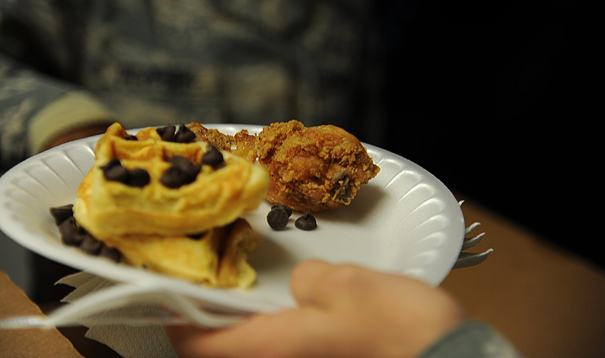 An Airman receives waffles and chicken during the Waffle ra-IDS at the Crossroads Student Center on Goodfellow Air Force Base, Texas, Oct. 27, 2015. The chaplains held the Waffle ra-IDS event to support Wingman Week. (U.S. Air Force photo by Airman Caelynn Ferguson/Released)