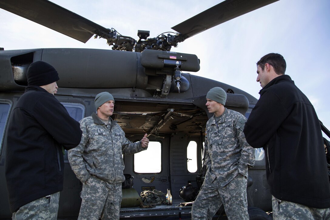 Army Chief Warrant Officer 4 Mark Ward, center left, briefs crew members on safety before conducting rescue hoist training on Joint Base Elmendorf-Richardson, Alaska, Oct. 21, 2015. Ward is a pilot assigned to the 1st Battalion, 207th Aviation Regiment, Alaska Army National Guard. The training included deploying a jungle penetrator device and practicing a simulated casualty evacuation with soldiers assigned to 1st Battalion, 501st Infantry Regiment. U.S. Air Force photo by Alejandro Pena