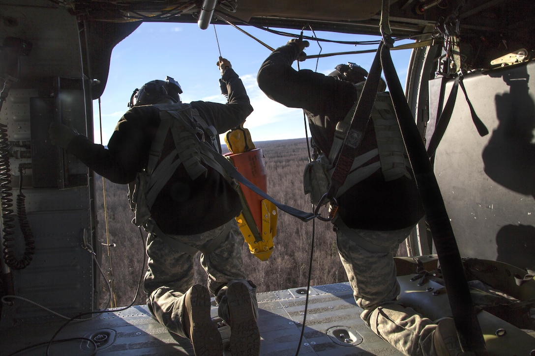 Army Sgt. Bradley McKenzie, left, and Staff Sgt. Kevan Katkus deploy a jungle penetrator while conducting rescue hoist training on Joint Base Elmendorf-Richardson, Alaska, Oct. 21, 2015. McKenzie and Katkus are crew chiefs assigned to the Alaska Army National Guard's 1st Battalion, 207th Aviation Regiment. U.S. Air Force photo by Alejandro Pena