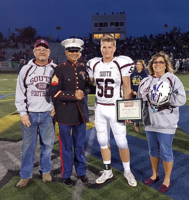 Sgt. Anthony S. Vizuete, canvassing recruiter with Recruiting Substation Toms River, presents Devin Murray, high school senior at Toms River High School South, with the Scholar Athlete Award at the Great American Rivalry Series Game between Toms River High School South and Toms River High School North, in Toms River, N.J., Sept. 25, 2015. 