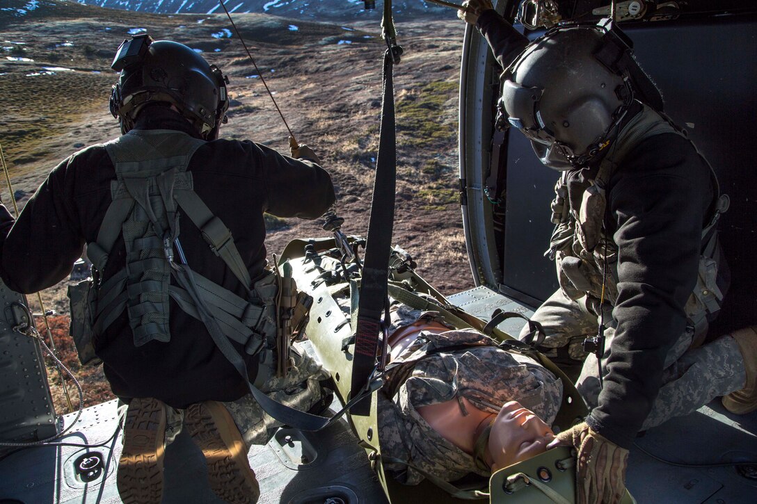 Army Sgt. Bradley McKenzie, left, and Staff Sgt. Kevan Katkus prepare to offload a stretcher carrying a simulated casualty to awaiting soldiers on Joint Base Elmendorf-Richardson, Alaska, Oct. 21, 2015. McKenzie and Katkus are crew chiefs assigned to the Alaska Army National Guard's 1st Battalion, 207th Aviation Regiment, and the soldiers are assigned to 1st Battalion, 501st Infantry Regiment. U.S. Air Force photo by Alejandro Pena