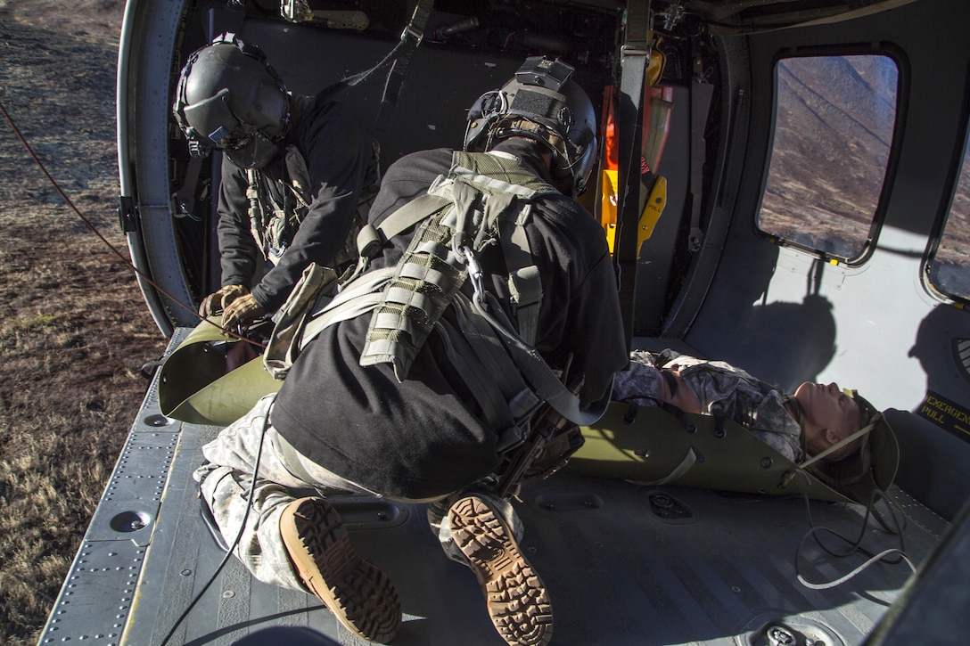 Army Staff Sgt. Kevan Katkus, left, and Sgt. Bradley McKenzie recover a simulated casualty while conducting rescue hoist training on Joint Base Elmendorf-Richardson, Oct. 21, 2015. Katkus and McKenzie and are crew chiefs assigned to the Alaska Army National Guard's 1st Battalion, 207th Aviation Regiment. U.S. Air Force photo by Alejandro Pena