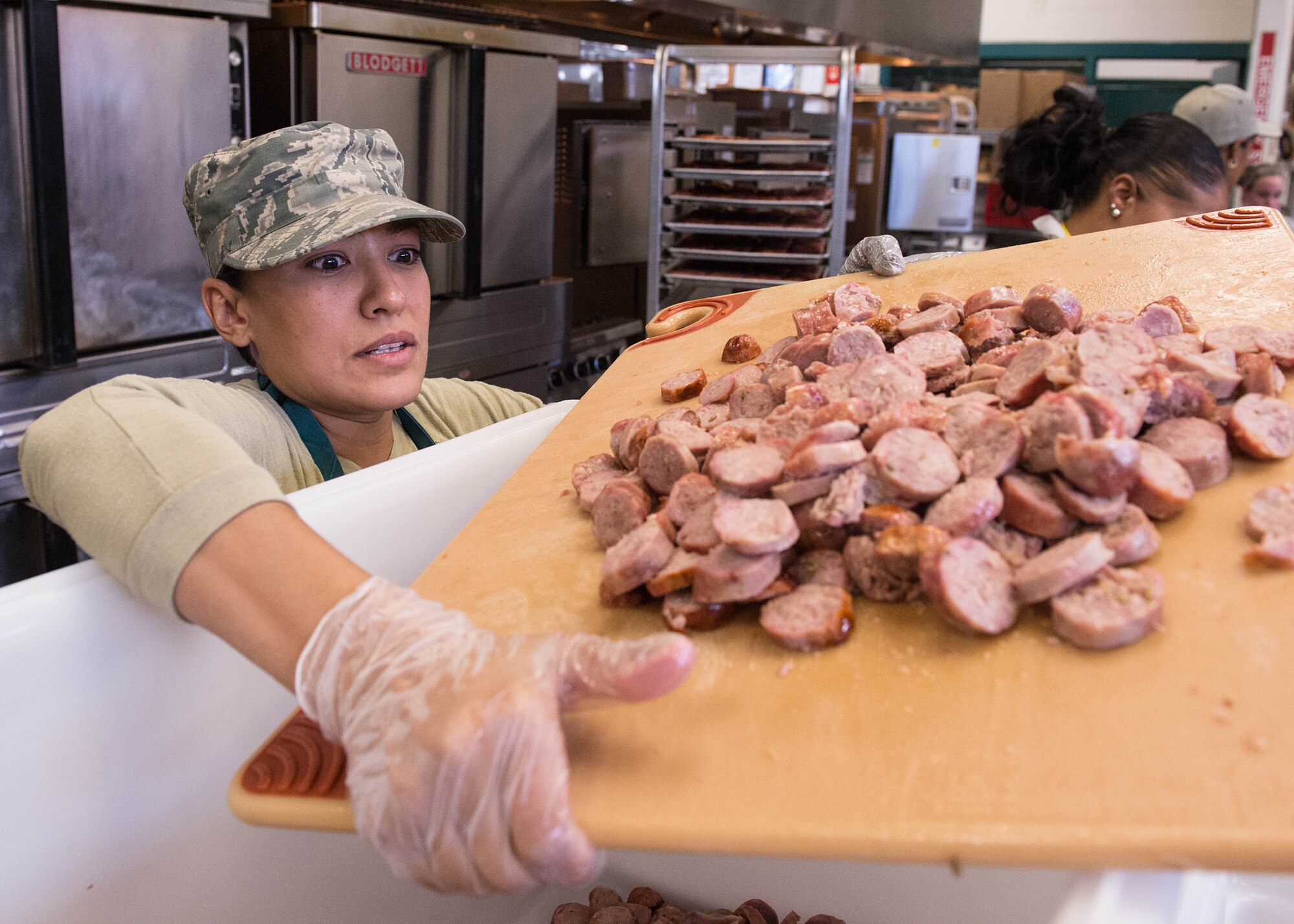 Staff Sgt. Kelly Portillo, a 66th Forces Support Squadron force management apprentice, transfers a cutting board full of sliced sausages destined for Jambalaya while volunteering at the Pine Street Inn Oct.26, 2015. Twelve Hanscom Airmen volunteered at the Pine Street Inn to prepare meals for more than 1,600 homeless men and women at three Boston area shelters. (U.S. Air Force photo/Jerry Saslav)