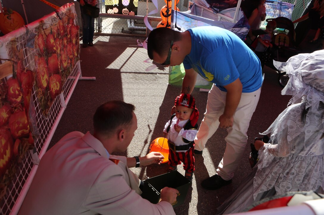 A service member with Marine Aircraft Group (MAG) 16 hands out candy to children during the MAG-16 Spooktacular aboard Marine Corps Air Station Miramar, Calif., Oct. 24. The Spooktacular also had a haunted hangar with zombies and clowns.