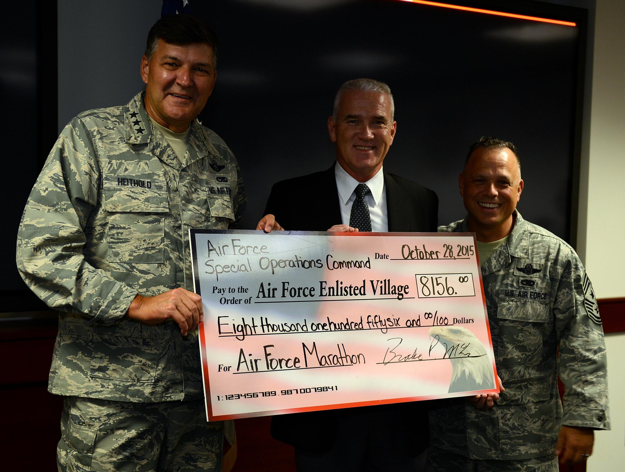 Lt. Gen. Brad Heithold, commander of Air Force Special Operations Command, presents a check to retired Chief Master Sgt. Brooke McLean, Air Force Enlisted Village CEO and president, at Hurlburt Field, Fla., Oct. 28, 2015. Air Commandos raised $8,156 running the 2015 Air Force Marathon at Wright-Patterson Air Force Base, Ohio. Chief Master Sgt. Matt Caruso, AFSOC command chief, (right) was recognized as one of the 13 AFSOC runners who participated in the Air Force Marathon or 9K. (U.S. Air Force photo/Senior Master Sgt. Quinton Burris) 