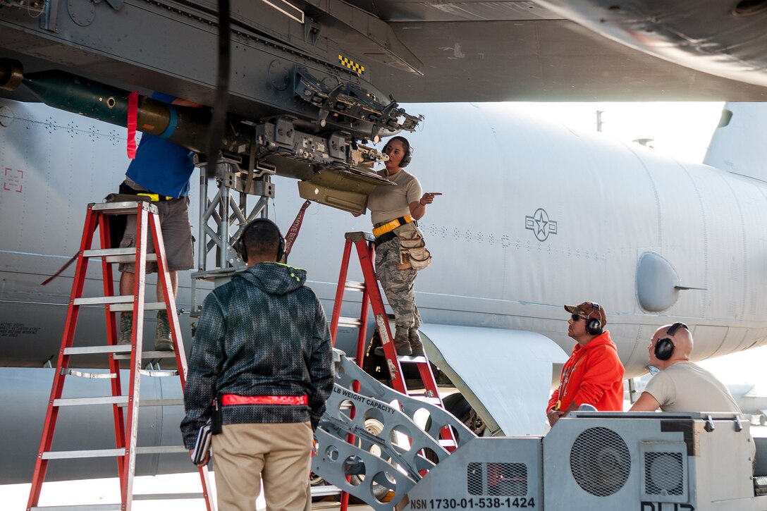 A U.S. Air Force weapons load crew is evaluated on the loading of an inert bomb onto the wing of a B-52 Stratofortress on Barksdale Air Force Base, La., on Oct. 22. The Total Force Integration crew from the Reserve 307th Aircraft Maintenance Squadron and the Active Duty 11th Aircraft Maintenance Unit are required to maintain a certification to be able to handle and load live munitions. (U.S. Air Force photo by Master Sgt. Dachelle Melville/Released)