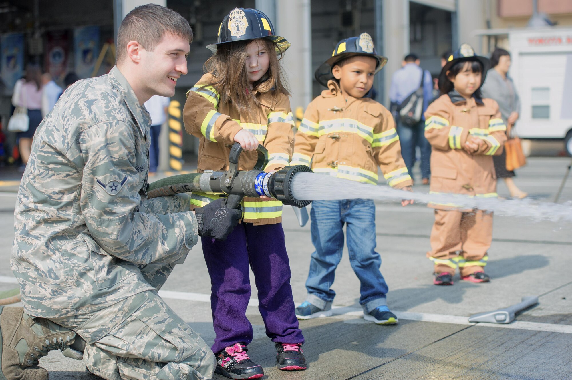 Airman Alex Harvell, 374th Civil Engineer Squadron firefighter, teaches children how to operate a fire hose during the Yokota fire emergency services 70th anniversary celebration at Yokota Air Base, Japan, Oct. 24, 2015. Team Yokota members gathered at the base’s main fire station to celebrate the 70 year history of Yokota’s fire emergency services. (U.S. Air Force photo by Airman 1st Class Delano Scott/Released) 