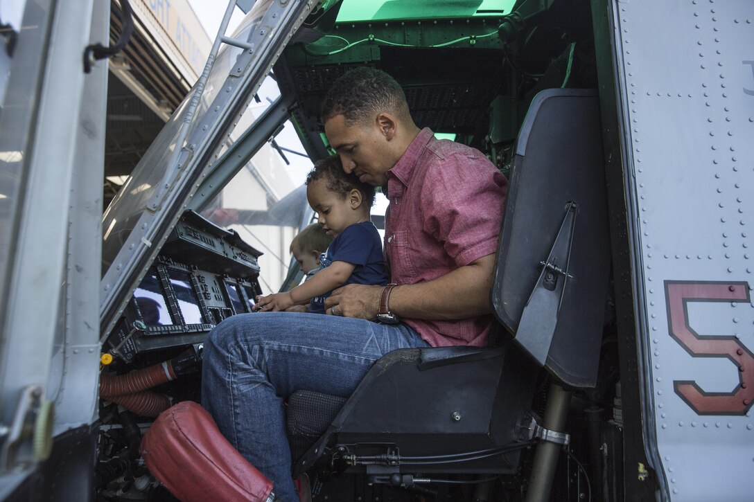 1st Lt. Daniel Sprott, a UH-1Y Huey Pilot with Marine Light Helicopter Attack Training Squadron (HMLAT) 303 and a Houston native, holds his son Daniel, while they sit in the cockpit of a Huey during the HMLAT-303 Family Day event aboard Marine Corps Air Station Camp Pendleton, Calif. Oct. 24. Marines with HMLAT-303 invited family members and guests of Marines to visit the squadron. (U.S. Marine Corps photo by Sgt. Lillian Stephens/Released)