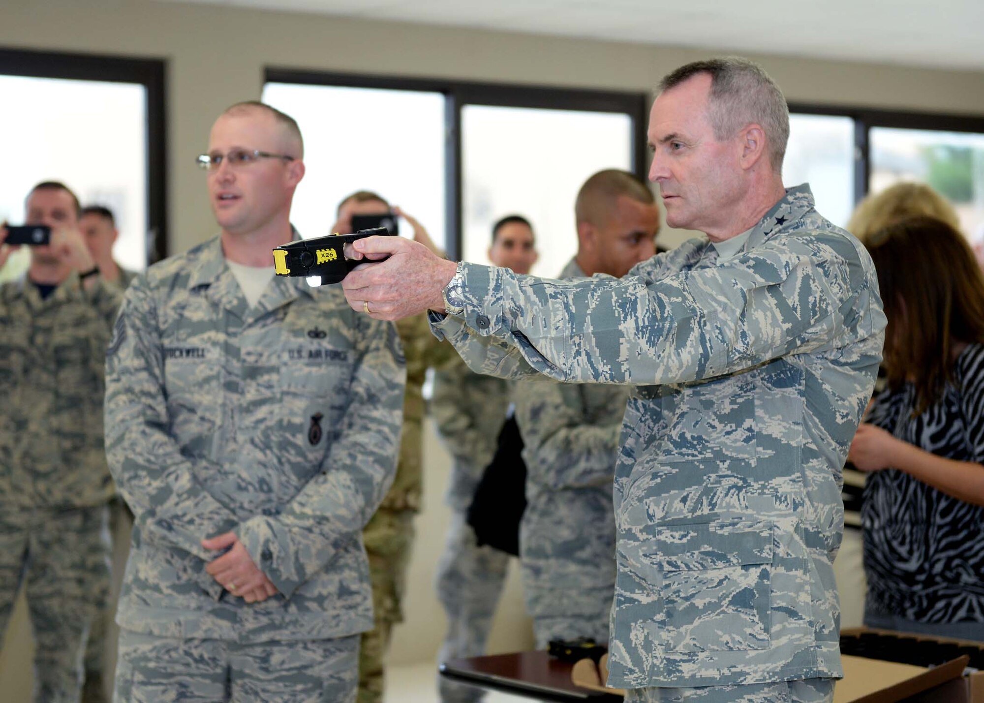 Tech. Sgt. Seth Stockwell, 343rd Training Squadron instructor, left, shows Lt. Gen. Darryl Roberson, commander, Air Education and Training Command, how to properly use a Taser during a tour of the 343rd TRS Oct. 23, 2015, at Joint Base San Antonio-Lackland, Texas. After shooting the device, the commander volunteered to experience a Taser discharge first hand, a requirement of all security forces members who carry the weapon. Roberson visited JBSA-Lackland as part of a tour of all AETC bases to learn about the mission and needs throughout the command. (U.S. Air Force photo by Staff Sgt. Marissa Garner)