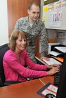 Capt. Marc Orcutt, 341st Medical Group practice manager, looks on as Laurie Trotman, 341st MDG Family Health Clinic office manager, schedules a patient Oct. 26, 2015. Orcutt is one six Medical Service Corps officers at Malmstrom Air Force Base, Mont., a career path that focuses on the business administration of hospitals and clinics. (U.S. Air Force photo/ John Turner)