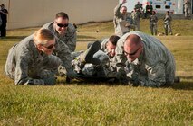 The 5th Medical Group Global Strike Challenge exec team low-crawls with a litter during a GSC competition at Minot Air Force Base, N.D., Oct. 19, 2015. The competition consisted of unloading a litter with a teammate on it, performing CPR on a dummy, along with running, climbing a wall and low crawling while carrying the litter. (U.S. Air Force photo/Airman 1st Class Sahara L. Fales)