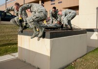 Members of a 5th Medical Group Global Strike Challenge team climb over an obstacle during a GSC competition at Minot Air Force Base, N.D., Oct. 19, 2015. The competition consisted of unloading a litter with a teammate on it, performing CPR on a dummy, along with running, climbing a wall and low crawling while carrying the litter. (U.S. Air Force photo/Airman 1st Class Sahara L. Fales)