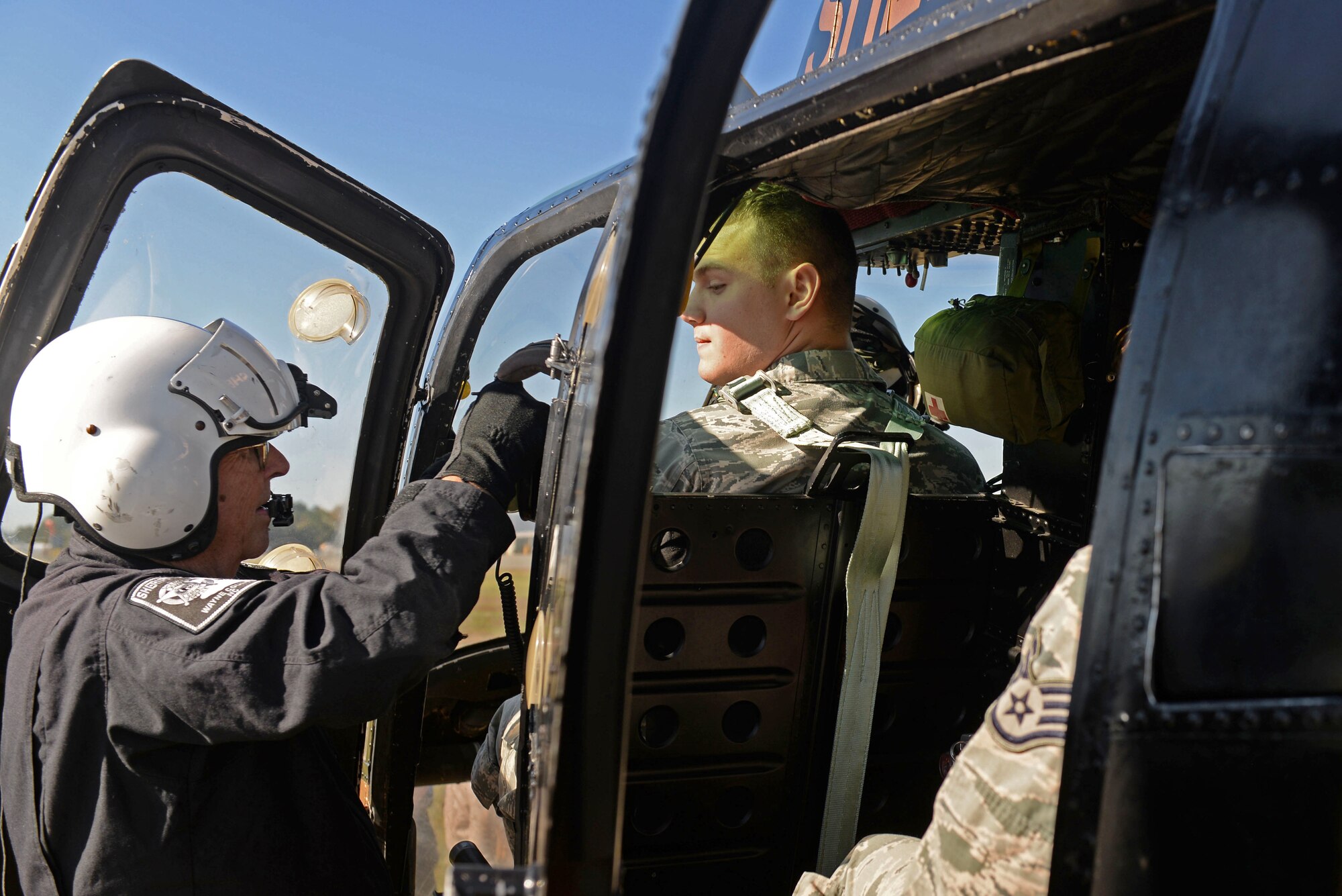 Senior Airman Tanner Sobleski, 4th Operations Support Squadron air traffic controller, is instructed by Lt. John Denny, Wayne County Sheriff’s Office aviation unit chief tactical flight officer, on how to fasten the seatbelts in a 1969 OH-58A+ helicopter, Oct. 21, 2015, at the Wayne Executive Jetport, Goldsboro, North Carolina. The 4th OSS air traffic controllers got a glimpse of the Wayne County Sheriff’s Office aviation unit’s operations in an effort to increase interoperability between the forces. (U.S. Air Force photo/Airman 1st Class Ashley Williamson)