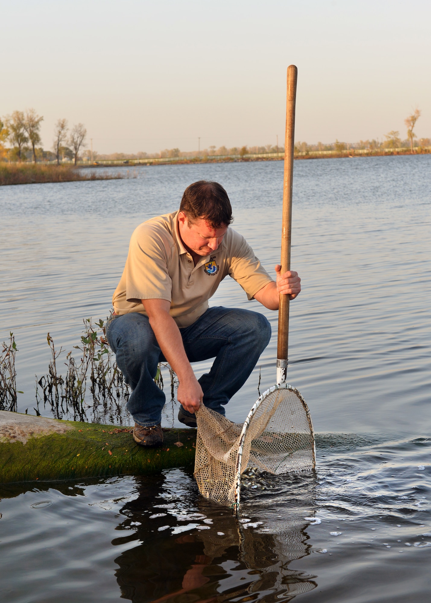 Dan James, U.S. Fish and Wildlife Service fish and wildlife biologist, releases redear sunfish into the Base Lake on Offutt Air Force Base, Neb., Oct. 19. The U.S. Fish and Wildlife Service and 55th CES will evaluate their survival and effectiveness as predators against zebra mussels in the future. (U.S. Air Force photo by Josh Plueger/Released)