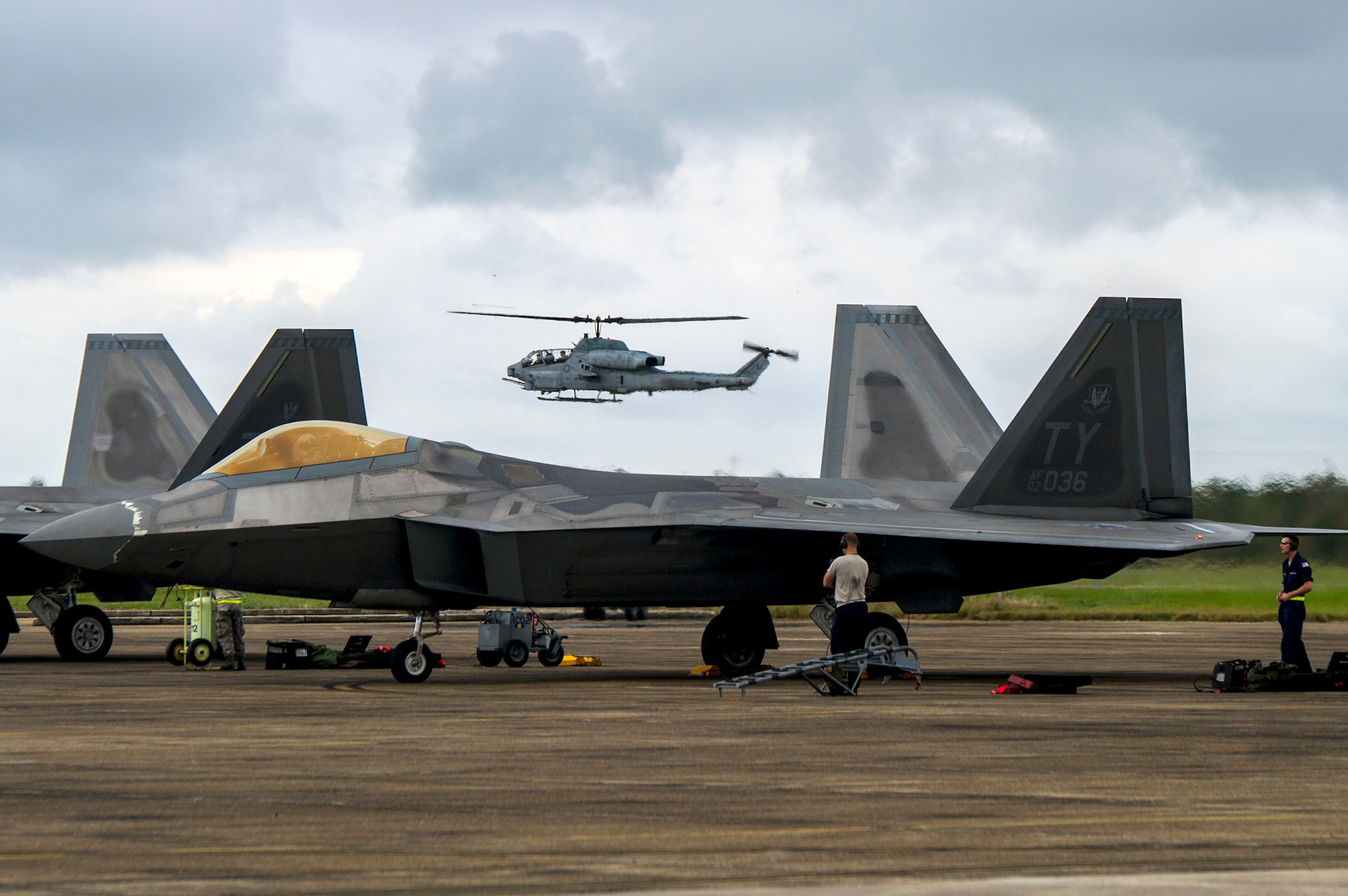 An AH-1W SuperCobra from Marine Light Attack Helicopter Squadron 773 Detachment A prepares to land as crew chiefs ready a Tyndall F-22 Raptor for take-off Oct. 27, 2015, during Exercise Southern Strike at Naval Air Station Joint Reserve Base Belle Chasse, La. Southern Strike allowed pilots to perform in a realistic environment and train with fourth and fifth generation fighters in high threat scenarios. (U.S. Air Force photo by Staff Sgt. Russ Jackson)