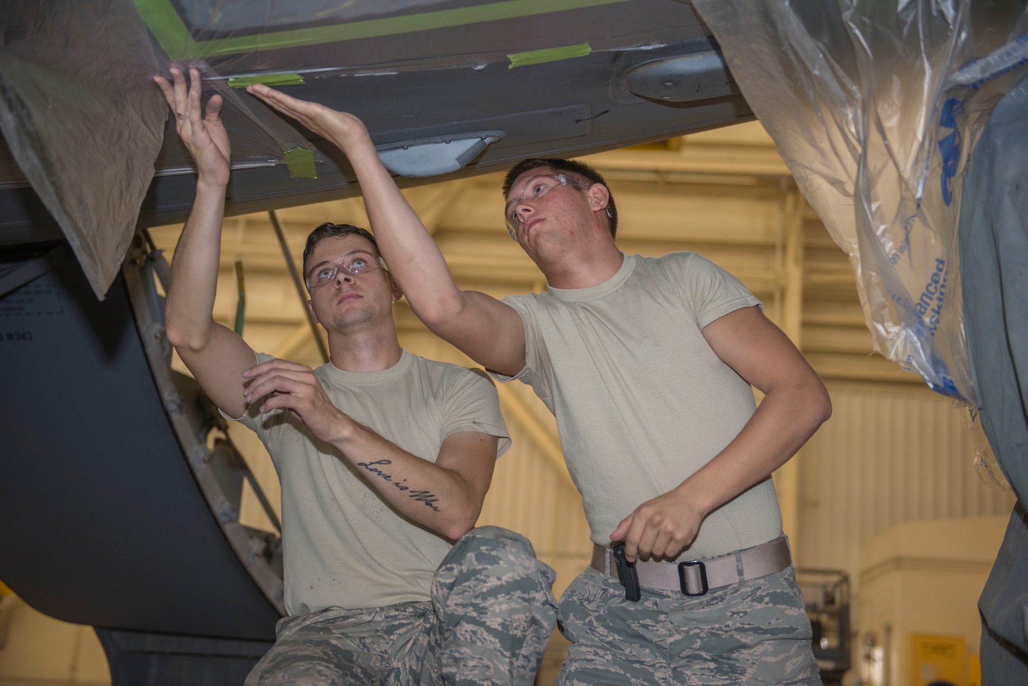(From left to right) 437th Maintenance Squadron aircraft structural maintainers, SrA Sean Locklear and A1C Matthew Hoofnagle, tape off sanded areas the C-17 Globemaster III’s skin  in building 515 at Joint Base Charleston – Air Base, S.C., on Oct. 15, 2015. By using the taping process, Hoofnagle and Locklear ensure only the proper areas of the fuselage are painted. (U.S. Air Force photo/Airman 1st Class Thomas T. Charlton)