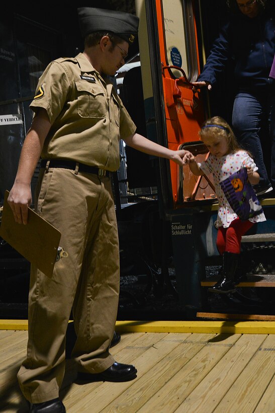 Jason Underwood, military role-player volunteer from Newport News, Va., helps Zelda Stebbins off a train car during Night at the Transportation Museum at Fort Eustis, Va., Oct. 26, 2015. This was the first year that the museum featured a train exhibit, which put participants through a mock screening for spies and demonstrated what rail travel was like during World Wars I and II. (U.S. Air Force photo by Staff Sgt. Natasha Stannard/Released)