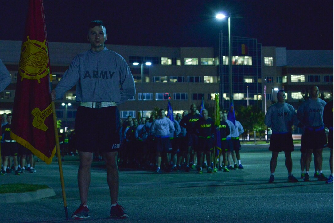 U.S. Army Pfc. Corey Musgrave, 597th Transportation Brigade transportation management coordinator, holds his brigade’s flag during the opening remarks of a Domestic Violence Awareness Month run at Fort Eustis, Va., Oct. 23, 2015. Service members ran with their units, mirroring the solidarity and support needed when faced with domestic violence. (U.S. Air Force  photo by Staff  Sgt. Natasha Stannard/Released)