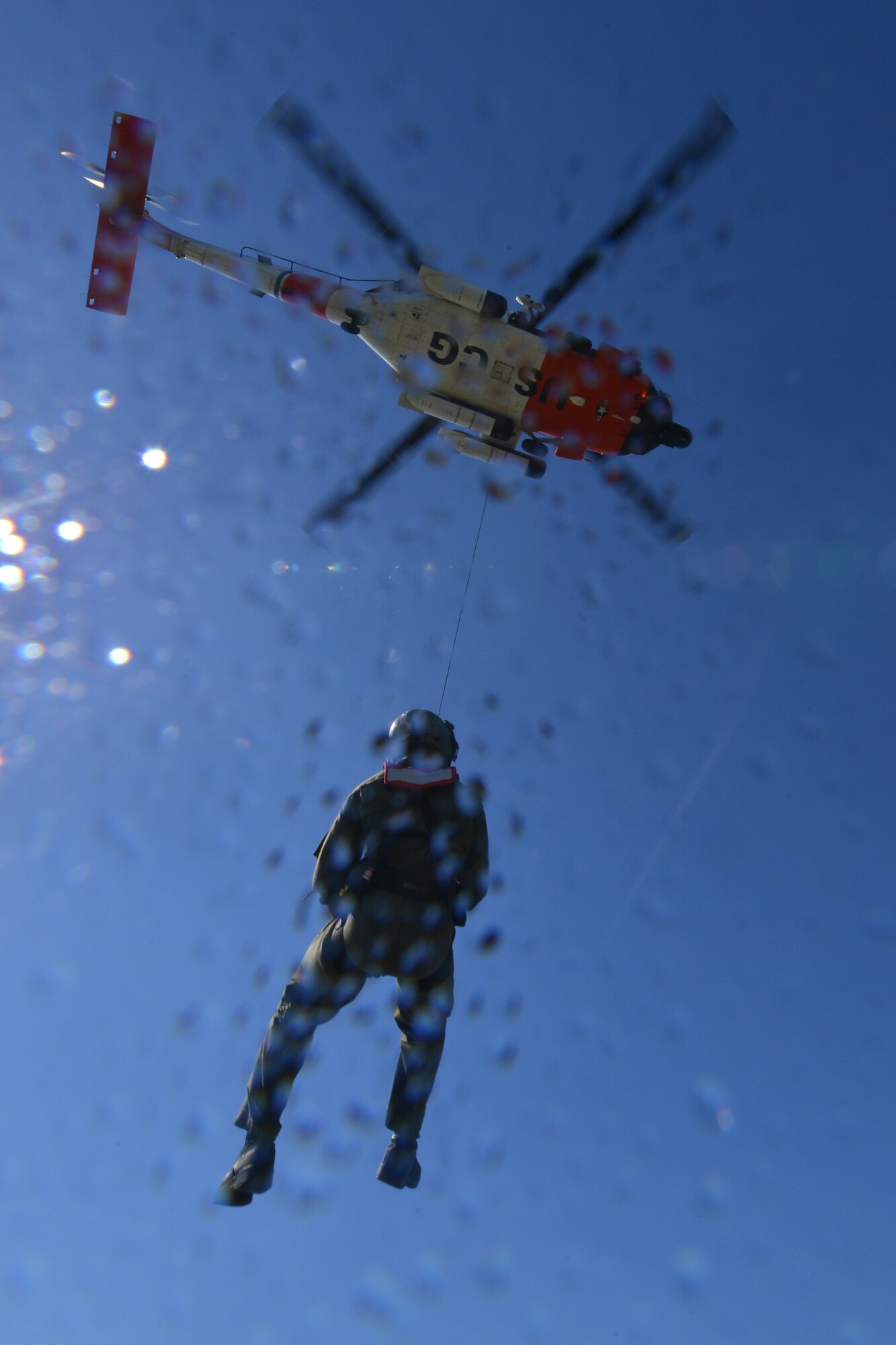 U.S. Coast Guard Petty Officer 3rd Class Kyle McCollum, Air Station Elizabeth City rescue swimmer, is hoisted to a helicopter after completing a joint casualty evacuation exercise with the 73rd Transportation Company U.S. Army tugboat MG Winfield Scott crew at Fort Eustis, Va., Oct. 21, 2015. The Service members teamed up to establish and understand processes and procedures, in case an emergency were to happen at sea both crews could spring into immediate action.  (U.S. Air Force photo by Staff Sgt. Natasha Stannard/Released)
