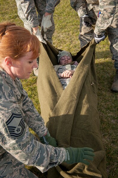 Senior Master Sgt. Jodi Flugel, member of the 5th Medical Group Global Strike Challenge flying penguins team, wraps her teammate in a blanket at Minot Air Force Base, N.D., Oct. 19, 2015. The competition consisted of unloading a litter with a teammate on it, performing CPR on a dummy, along with running, climbing a wall and low crawling while carrying the litter. (U.S. Air Force photo/Airman 1st Class Sahara L. Fales)