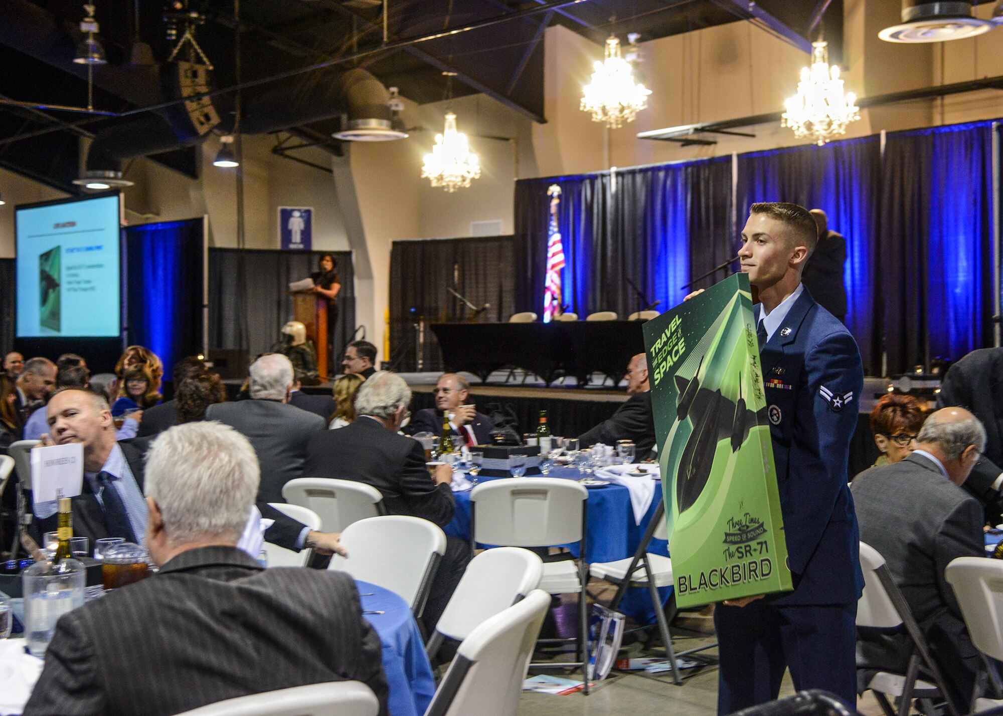 Airman 1st Class Cory Bond, 412th Communications Squadron, shows a poster of the SR-71 during the live auction at the annual Gathering of Eagles. (U.S. Air Force photo by Rebecca Amber)