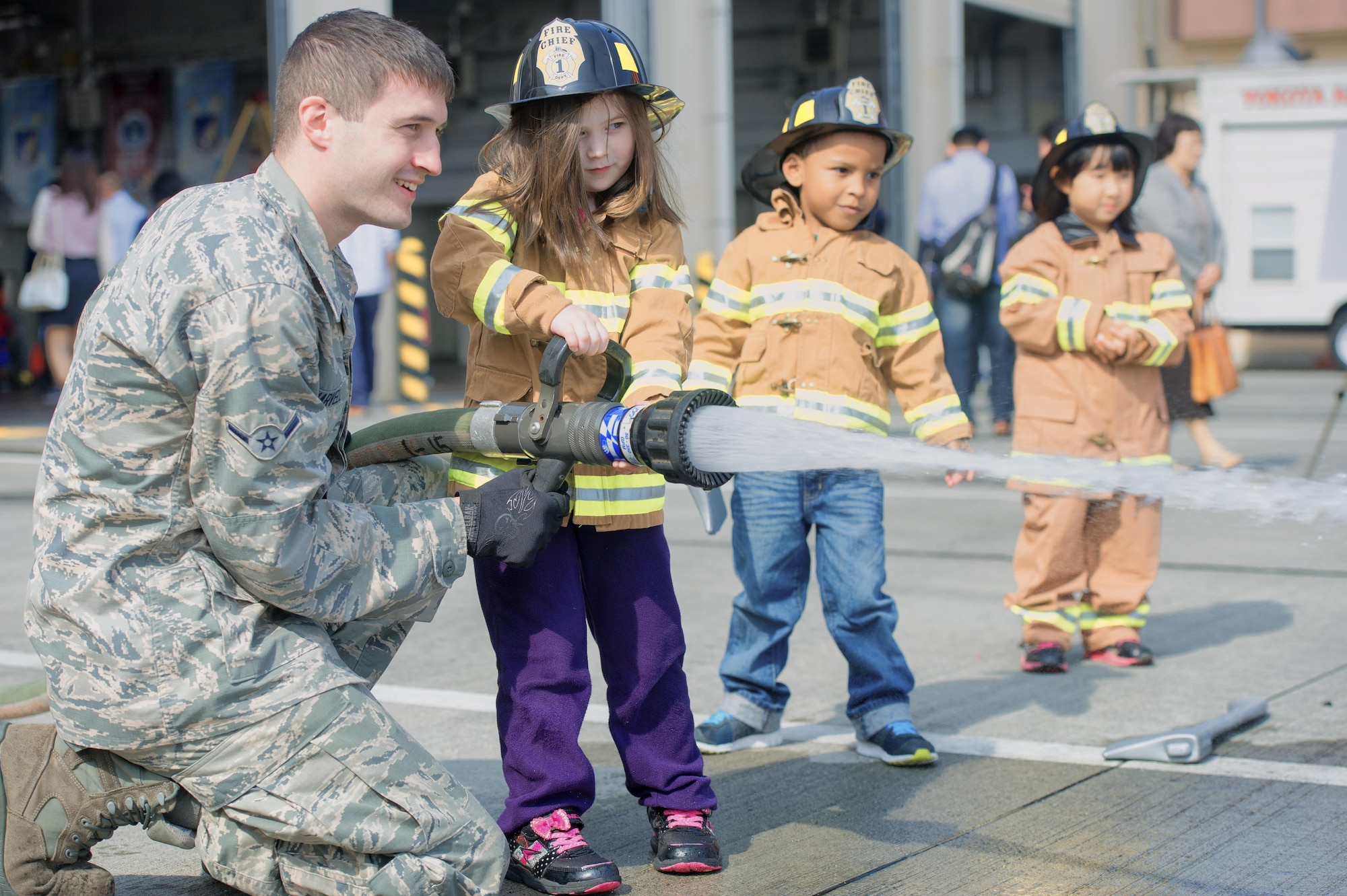 Airman Alex Harvell, 374th Civil Engineer Squadron firefighter, teaches children how to operate a fire hose during the Yokota fire emergency services 70th anniversary celebration at Yokota Air Base, Japan, Oct. 24, 2015. Team Yokota members gathered at the base’s main fire station to celebrate the 70 year history of Yokota’s fire emergency services. (U.S. Air Force photo by Airman 1st Class Delano Scott/Released)   