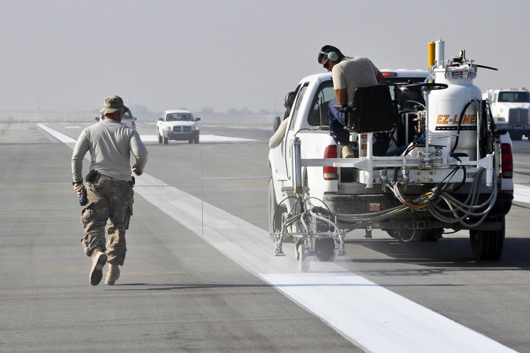 U.S. airmen paint runway markings on Bagram Airfield, Afghanistan, Oct. 22, 2015. The airmen are assigned to the 455th Expeditionary Civil Engineer Squadron. U.S. Air Force photo by Tech. Sgt. Nicholas Rau