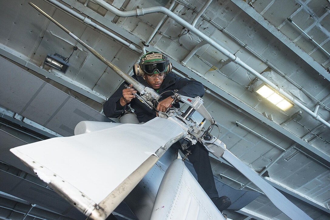 U.S. Navy Airman Christian Clark attaches weights to the tail rotor of an MH-60R Seahawk in the hangar bay of the USS George Washington in the Pacific Ocean, Oct. 26, 2015. The Seahawk is assigned to Helicopter Maritime Strike Squadron 78. U.S. Navy photo by Petty Officer 3rd Class Jaime Marcial