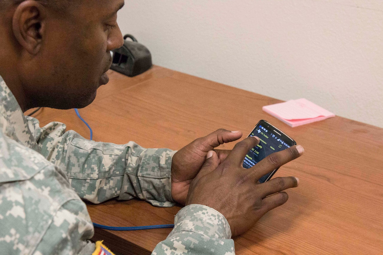 Army Sgt. 1st Class Ronnie Russell, mortar platoon sergeant for Headquarters and Headquarters Company, 1st Battalion, 12th Cavalry Regiment, scrolls down the social media feed of local law enforcement agencies in Tx Corral, one of the mobile apps that he created to give his fellow soldiers easy access to information. U.S. Army photo by Staff Sgt. Leah R. Kilpatrick