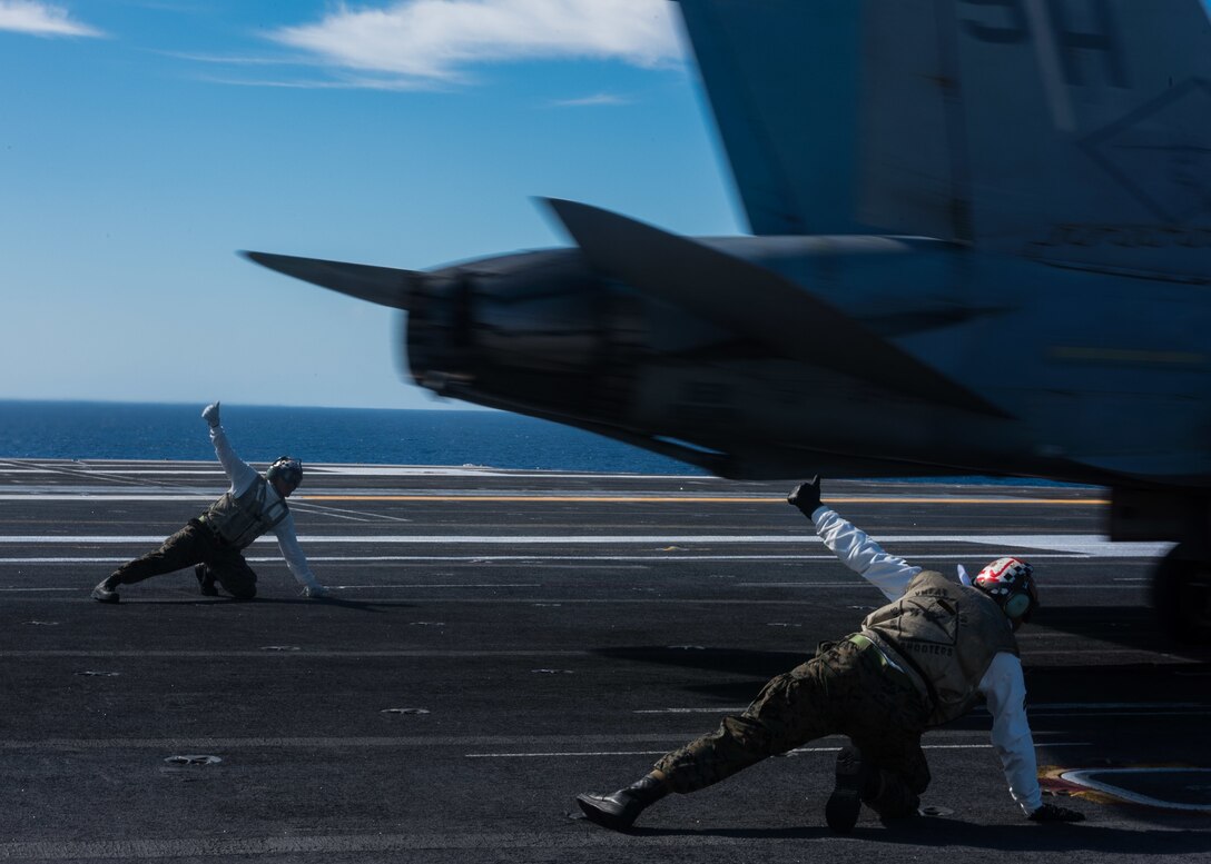 U.S. Corps Marine Sgt. Anexys Torrescastro and U.S. Marine Corps Cpl. Brandon Vizcaya signal that an F/A-18C Hornet assigned to the Sharpshooters of Marine Fighter Attack Training Squadron 101 is ready for takeoff from the flight deck of the USS John C. Stennis in the Pacific Ocean, Oct. 23, 2015. U.S. Navy photo by Petty Officer 3rd Class Kenneth Rodriguez Santiago
