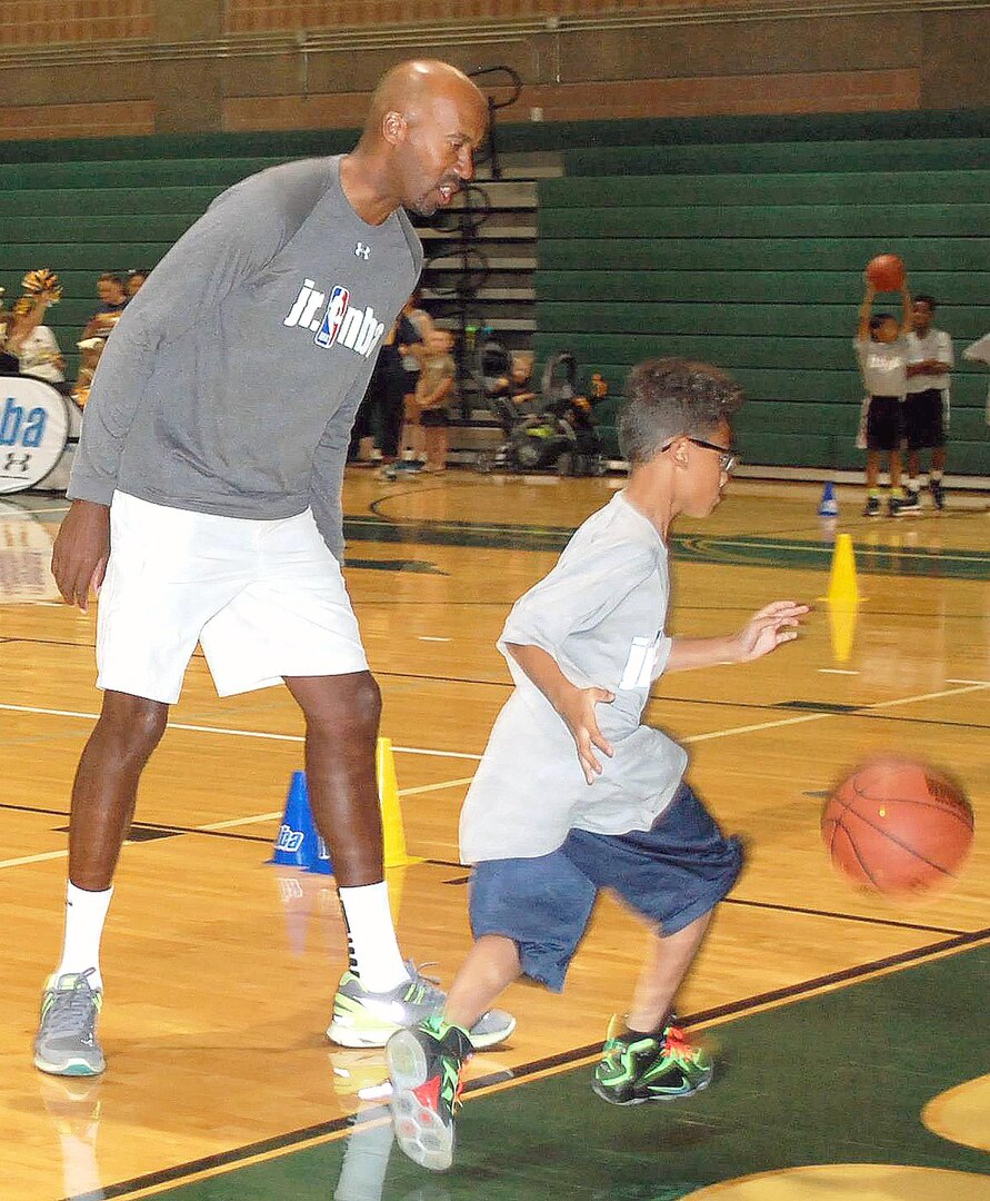 Bruce Bowen, former San Antonio Spurs legend and current ESPN analyst, encourages Jr. NBA clinic participants during a dribbling drill at Cole High School on Joint Base San Antonio-Fort Sam Houston Oct. 19. Bowen shared his enthusiasm for the sport, physical fitness and healthful living with the participants and their family members.