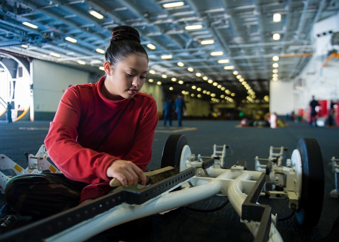 U.S. Navy Seaman Allison Boutwell removes rust from weapon support equipment in the hangar bay aboard the USS John C. Stennis in the Pacific Ocean, Oct. 24, 2015. Boutwell is an aviation ordnanceman airman. U.S. Navy photo by Petty Officer 3rd Class Jonathan Jiang