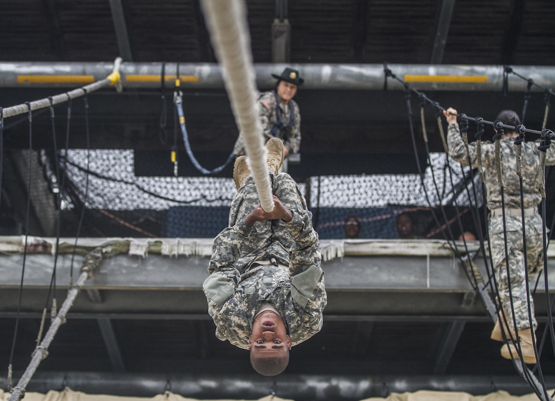 After losing his balance on a rope bridge obstacle, a Soldier in Basic Combat Training with E Company, 2nd Battalion, 39th Infantry Regiment, attempts to complete the task by using pure upper body strength to shimmy across to the other side with his Drill Sgt. looking on, Oct. 28, 2015. Soldiers in Basic Combat Training must complete all tasks at Victory Tower on Fort Jackson, S.C., which also boasts a 40-foot repelling wall, in order to graduate. (U.S. Army photo by Sgt. 1st Class Brian Hamilton)