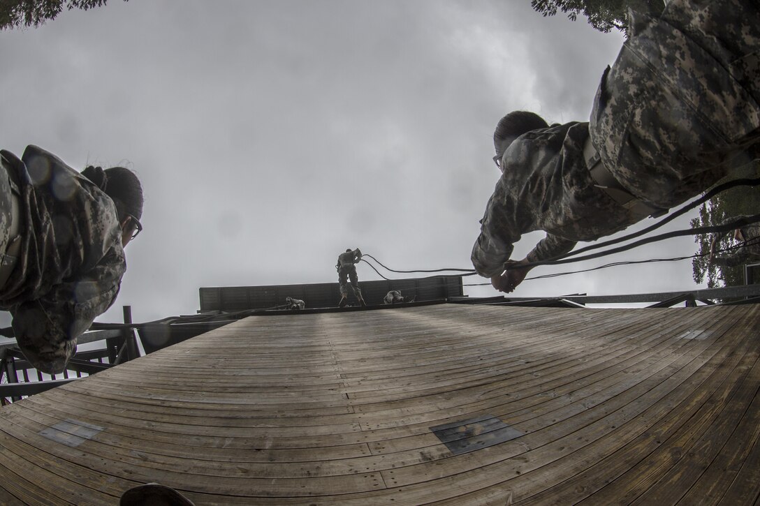 Soldiers in Basic Combat Training with E Company, 2nd Battalion, 39th Infantry Regiment, stand ready on belay on a rainy fall morning as Soldiers repel down the 40-foot wall at Victory Tower on Fort Jackson, S.C., Oct. 28, 2015. The Soldier on belay serves as a safety for the Soldier repelling. In the event of a free-fall, the belay will pull straight down on the rope to stop the repeller almost instantly. (U.S. Army photo by Sgt. 1st Class Brian Hamilton)