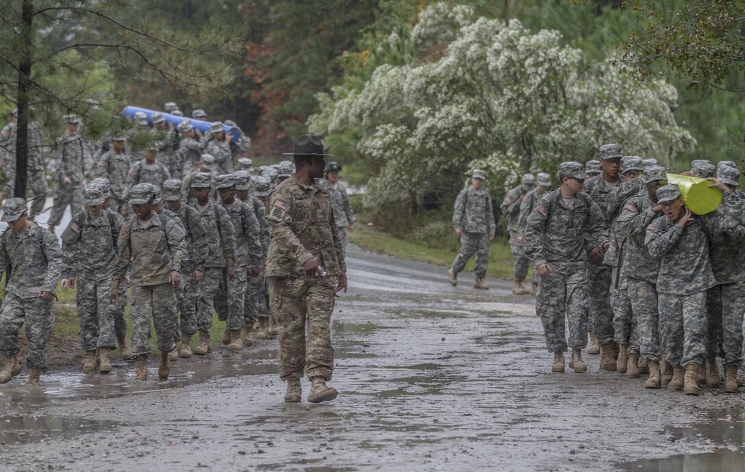 On a rainy, windy morning at Fort Jackson, S.C., Soldiers in Basic Combat Training with E Company, 2nd Battalion, 39th Infantry Regiment, march into the Victory Tower complex, Oct. 28, 2015. The Soldiers are carrying logs to emphasize the importance of working as a team. (U.S. Army photo by Sgt. 1st Class Brian Hamilton)