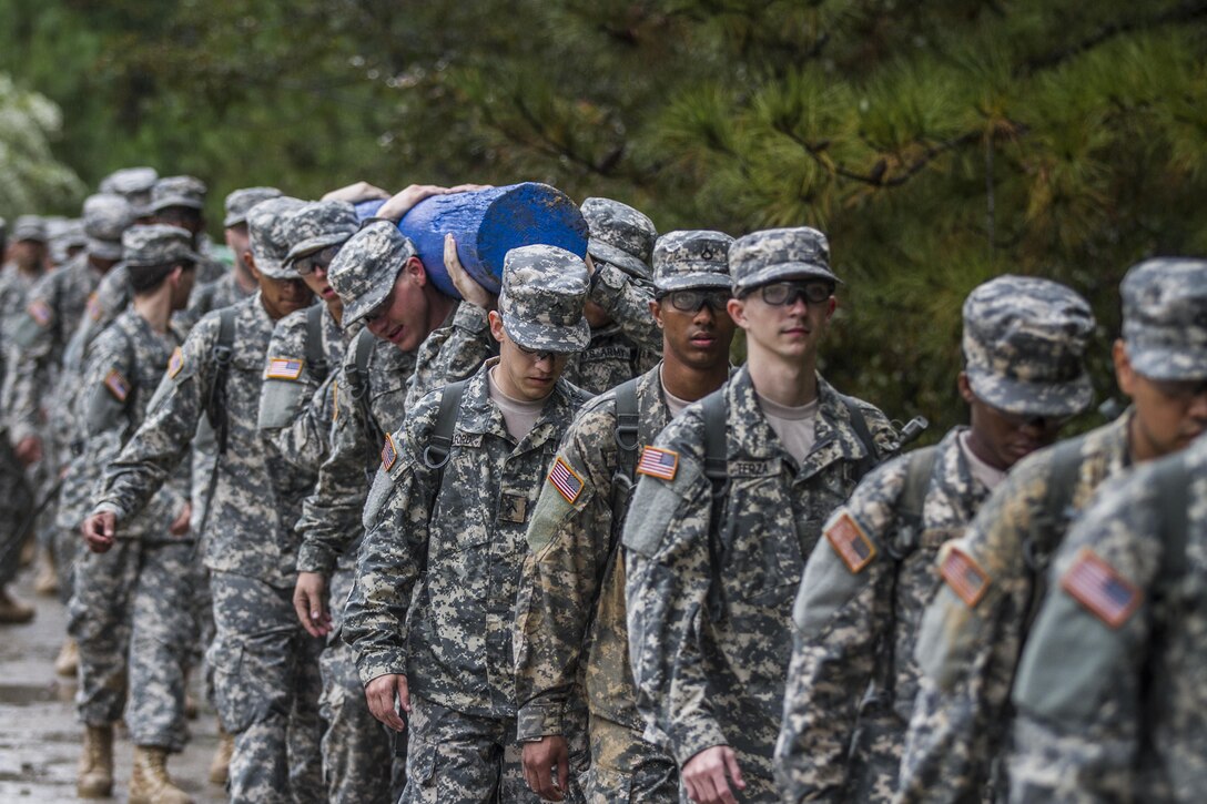 On a rainy, windy morning at Fort Jackson, S.C., Soldiers in Basic Combat Training with E Company, 2nd Battalion, 39th Infantry Regiment, march into the Victory Tower complex, Oct. 28, 2015. The Soldiers are carrying logs to emphasize the importance of working as a team (U.S. Army photo by Sgt. 1st Class Brian Hamilton)