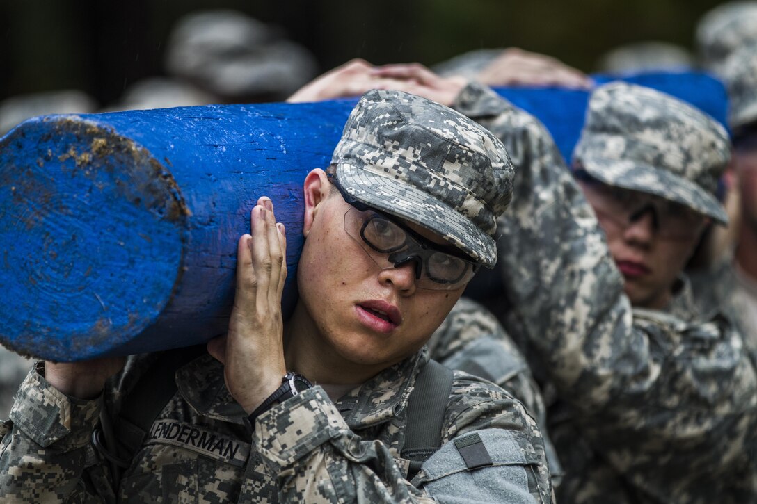 On a rainy, windy morning at Fort Jackson, S.C., Soldiers in Basic Combat Training with E Company, 2nd Battalion, 39th Infantry Regiment, march into the Victory Tower complex, Oct. 28, 2015. The Soldiers are carrying logs to emphasize the importance of working as a team. (U.S. Army photo by Sgt. 1st Class Brian Hamilton)